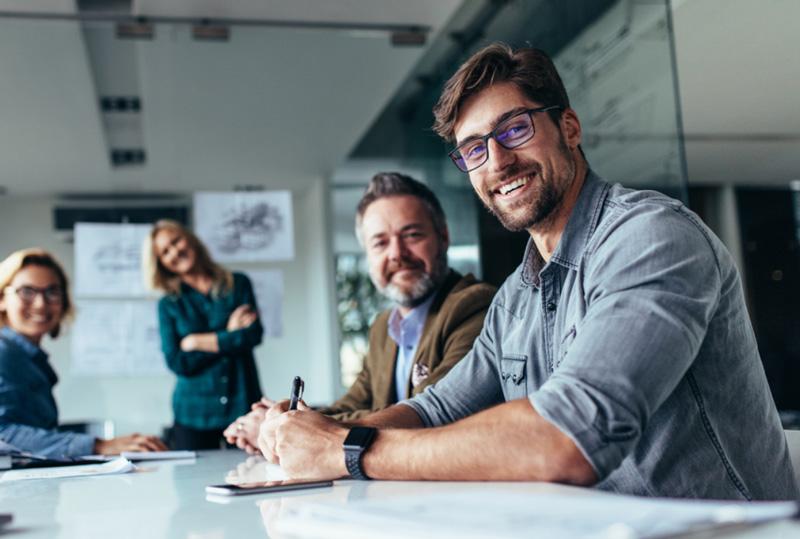 Four people in a meeting, smiling at the camera