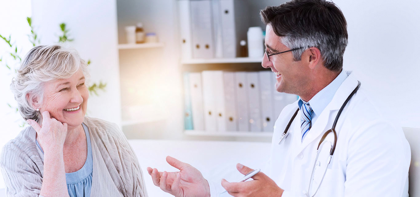 Older female patient smiling with an older male healthcare professional