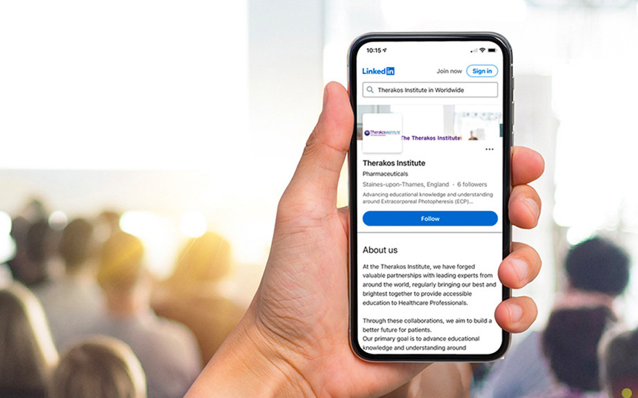 Hand holding a smartphone showing the Therakos Institute page on LinkedIn